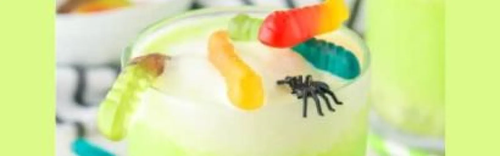 Closeup of green punch topped with gummy worms.