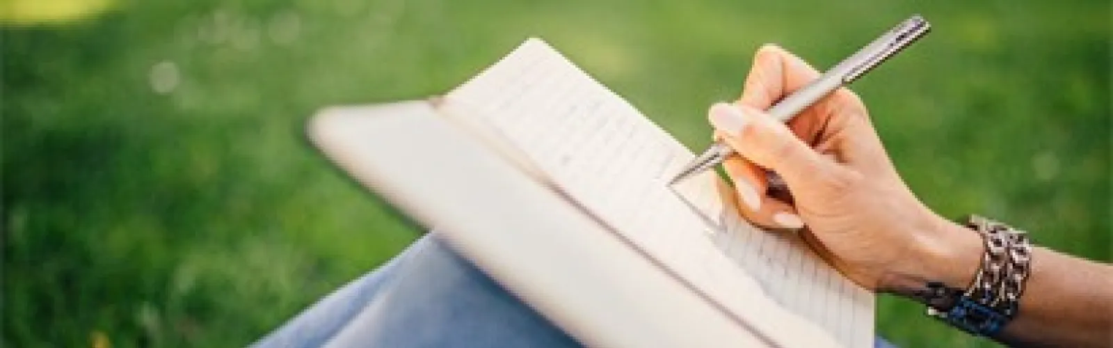 Woman writing in a journal held on her knees.