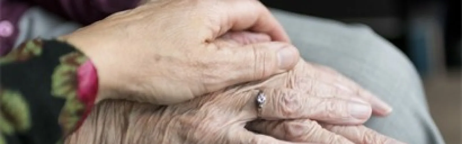 A woman's hand resting on top of an elderly woman's hand.
