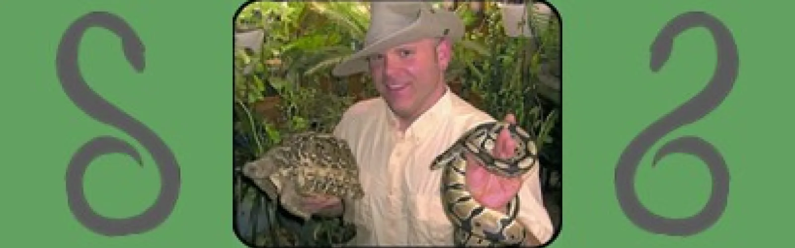 Animal handler Mark wears a safari outfit and holds a torise and a snake.