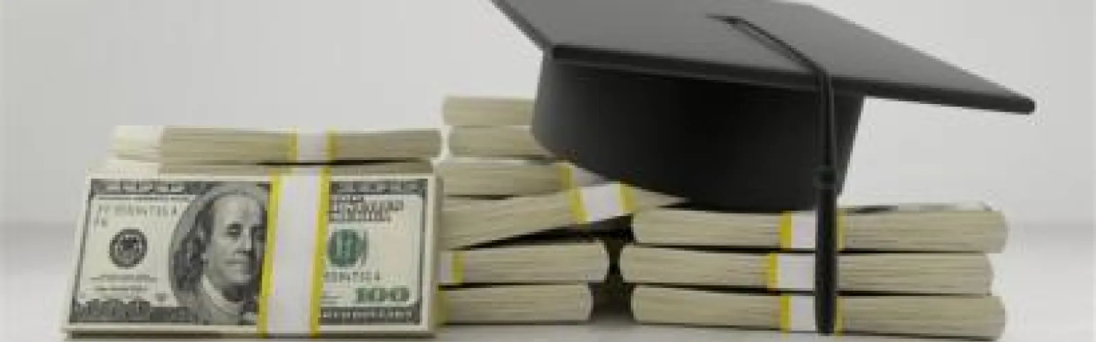 Graduation cap sitting on top of stacks of $100 bills.