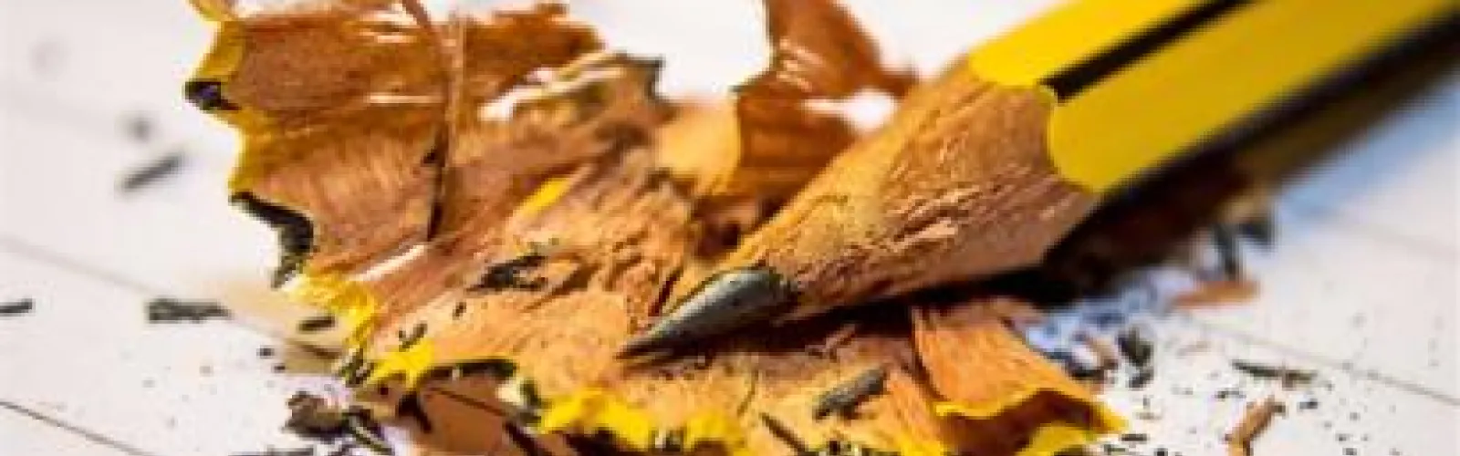 A yellow pencil sharpened to a fine point sits in a pile of shavings.
