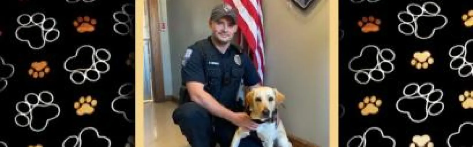 A young officer kneels beside a yellow lab dog.